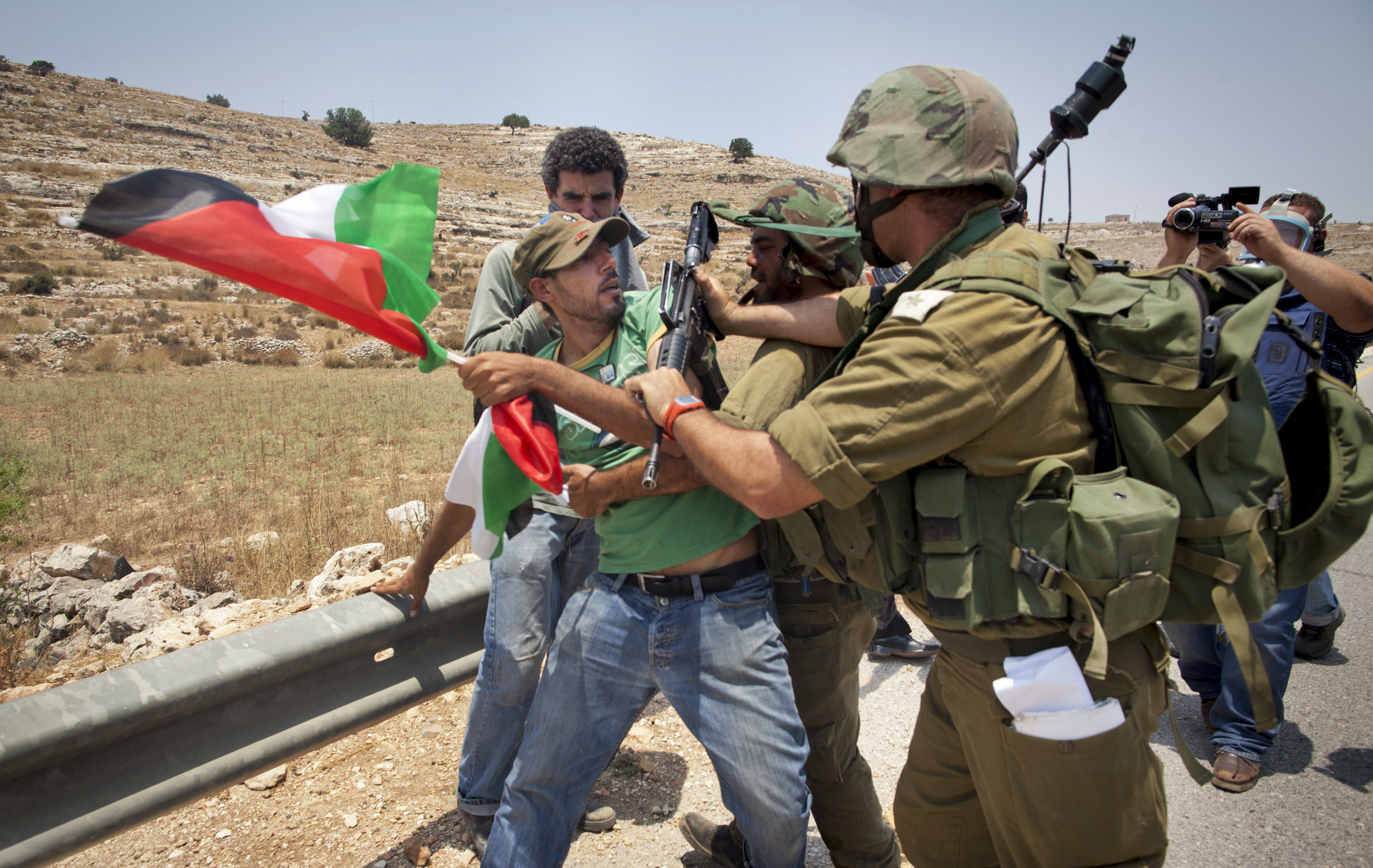 An unidentified protester holding a Palestinian flag scuffles with Israeli security forces during a joint pro-Palestinian demonstration held by foreign, Israeli and Palestinian demonstrators in the West Bank village of Nabi Saleh, Saturday, July 9, 2011. Some of the international pro-Palestinian activists questioned at Israel's airport over the weekend have reached the West Bank and participated in anti-Israel protests Saturday. (AP Photo/Oren Ziv)