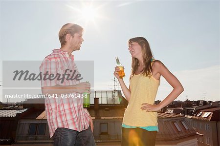 641-03761438 © Masterfile Royalty-Free Model Release: Yes Property Release: No Germany, Bavaria, Munich, Young couple talking and enjoying beer on rooftop